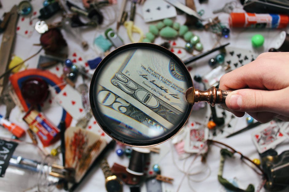 Image description: A person holding a magnifying glass in front of a computer screen with a puzzle icon on it.